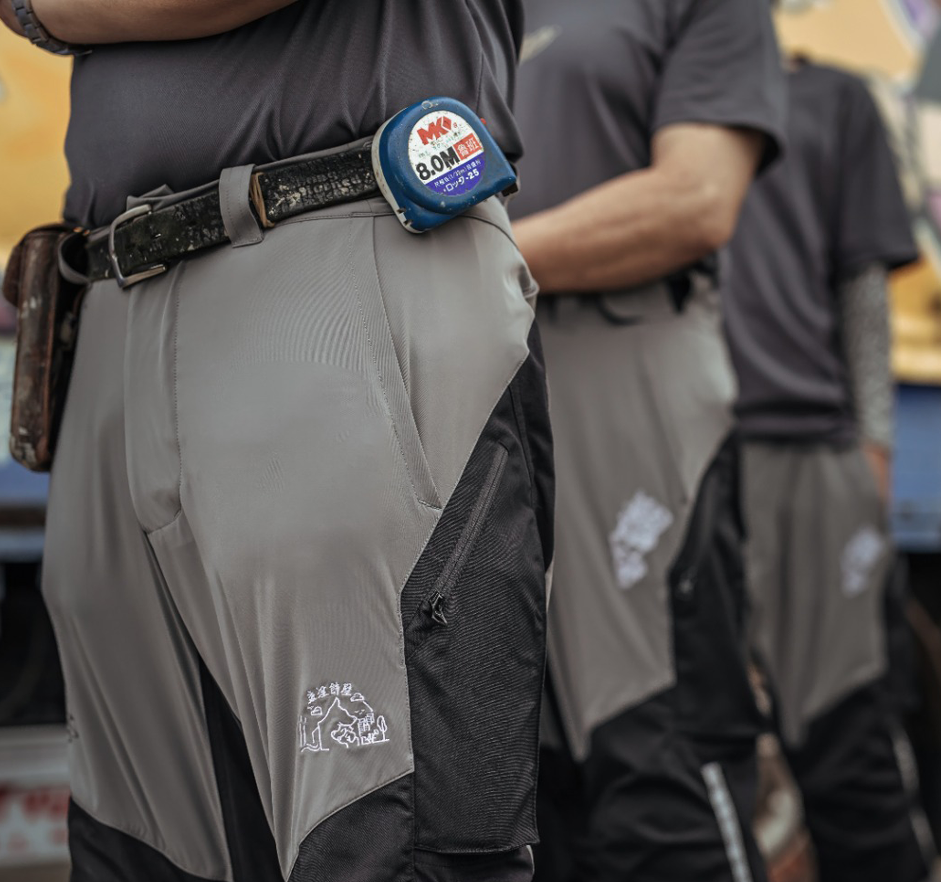 TMS.SITE logo placement: three workers lined up, wearing their TMS.SITE work pants with custom logo placement.