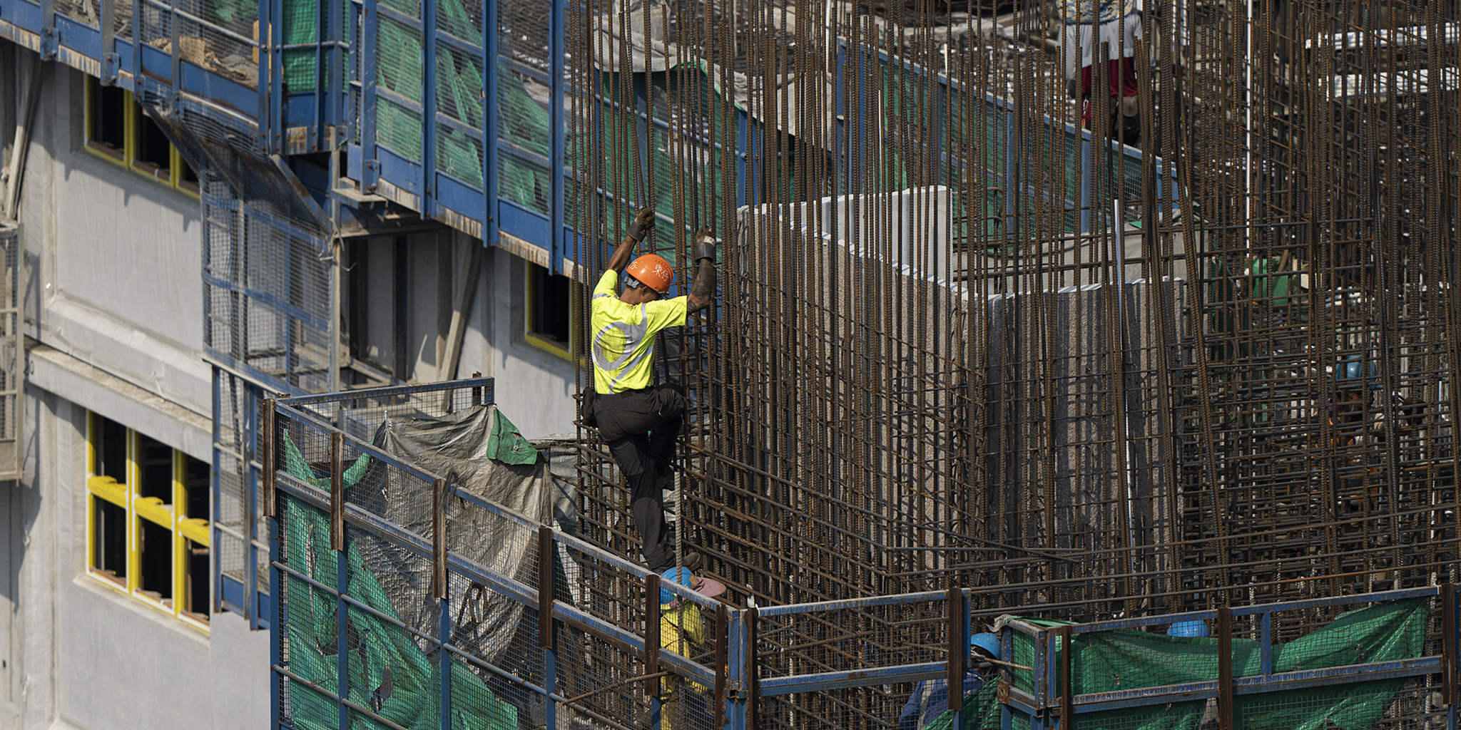 TMS.SITE home: A construction worker wearing TMS.SITE, climbing steel bars in Hong Kong