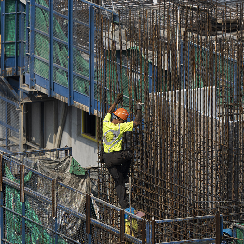 TMS.SITE home: A construction worker wearing TMS.SITE, climbing steel bars in Hong Kong